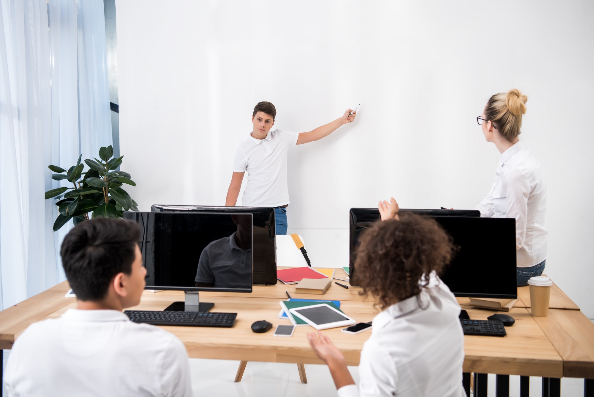 young teenager pointing on white board in classroom with students